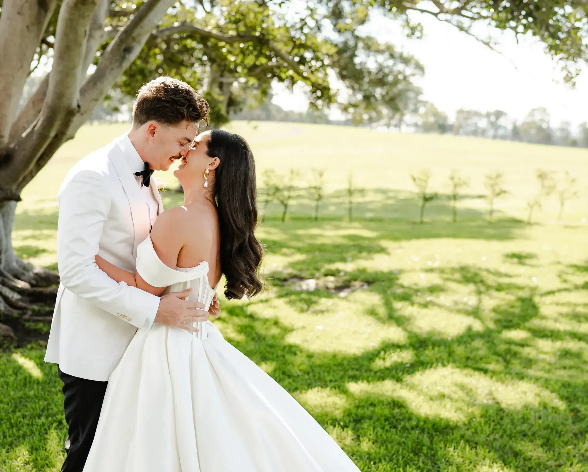 Couple sharing romantic moment under tree in sunlit field