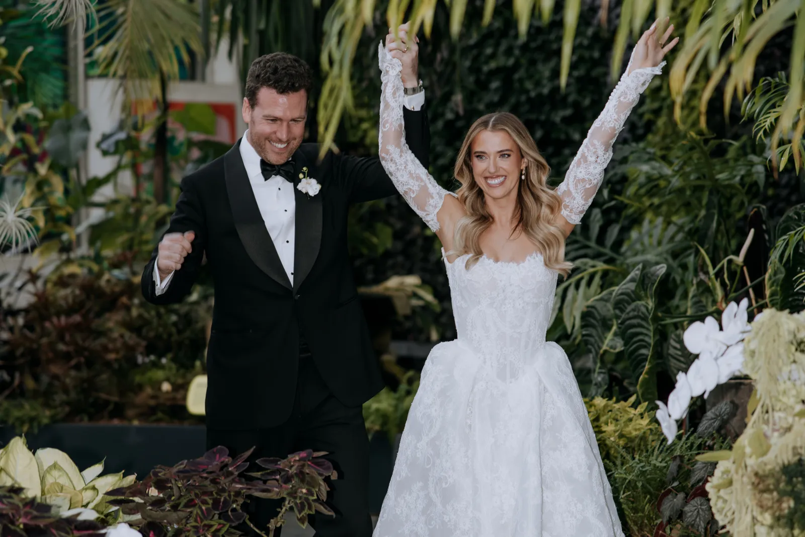 Couple celebrating as they walk back down the aisle in a garden ceremony