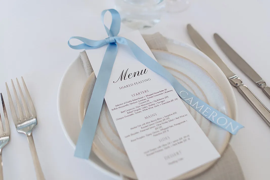 Wedding place setting with a printed menu tied with a pale blue ribbon