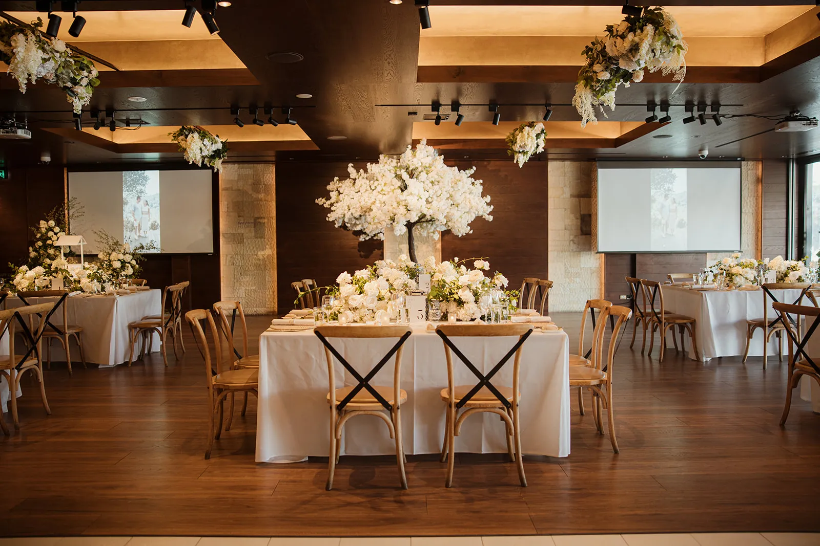 Styled wedding reception room with white florals and cross-back chairs