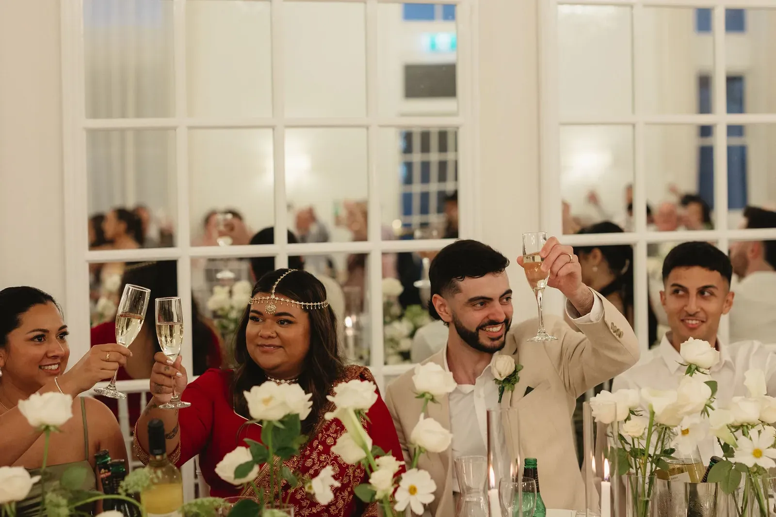 Guests raising champagne glasses at a styled reception table during speeches