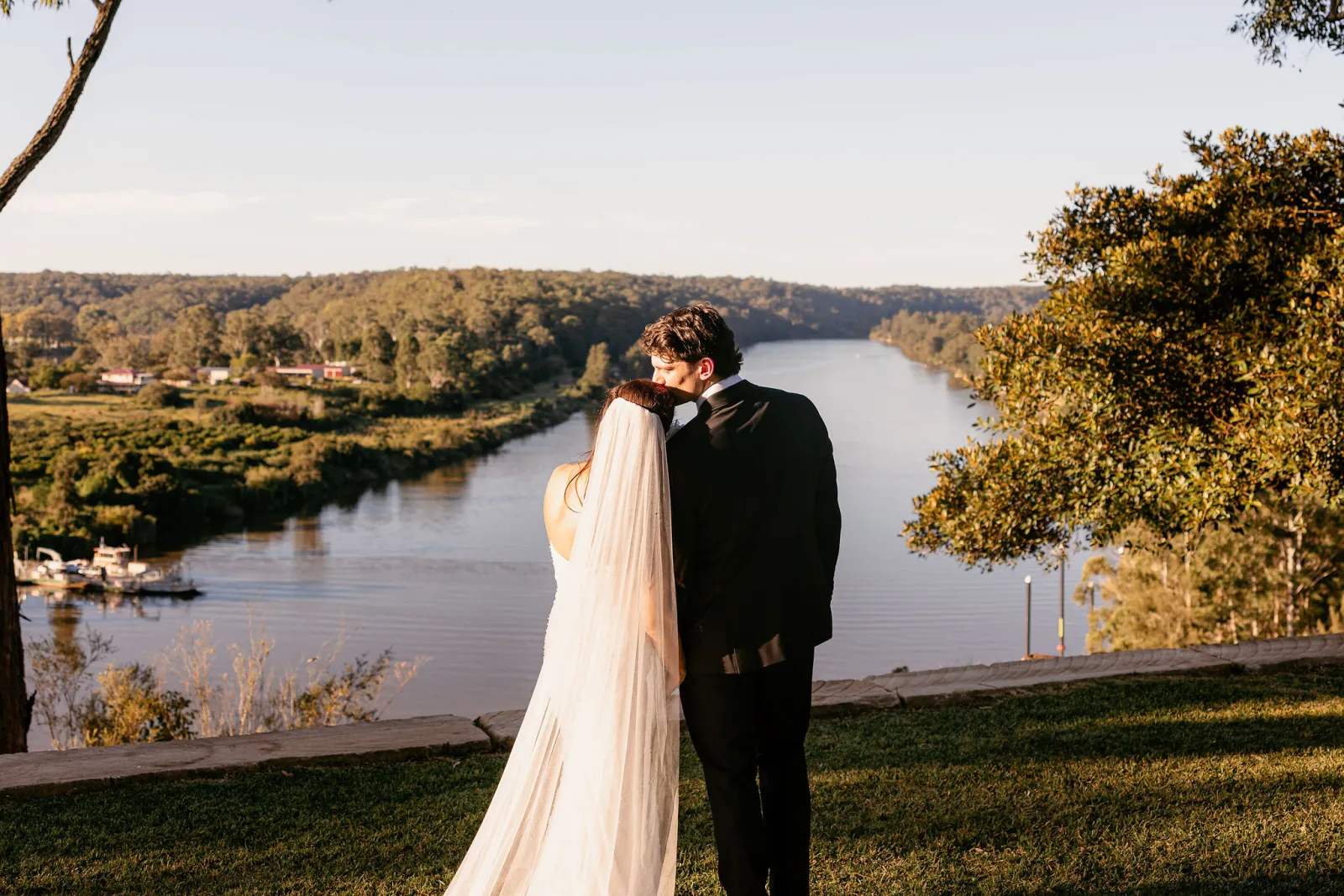 Couple kissing at a lookout above the river at golden hour