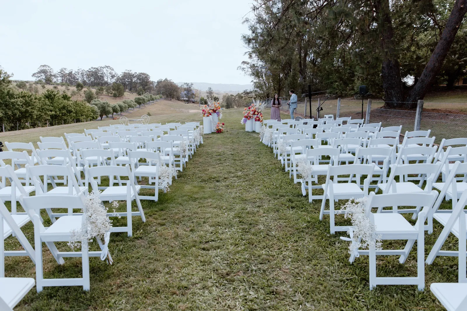 Rows of white folding chairs on a grass aisle for a rural NSW ceremony