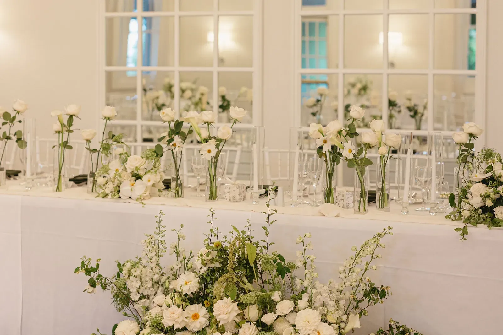 Styled wedding head table with white florals, candles and glassware before guests arrive